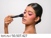 woman wearing pink makeup and holding a blush brush. Isolated on white background. Стоковое фото, агентство Ingram Publishing / Фотобанк Лори