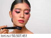woman wearing pink makeup and holding a blush brush. Isolated on white background. Стоковое фото, агентство Ingram Publishing / Фотобанк Лори