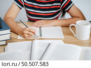 a young woman working in a book on the table. Стоковое фото, агентство Ingram Publishing / Фотобанк Лори