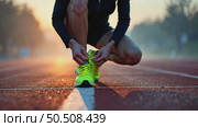 A close-up of a runner tying their neon running shoes on a misty morning track, their breath visible in the cold air. Стоковое AI-видео, аниматор Sergey Grishin / Фотобанк Лори