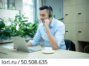 Young man working at a call center which is a consultant for various information of customers who call to inquire or ask for advice with a happy mood. Стоковое фото, агентство Ingram Publishing / Фотобанк Лори