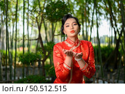 Portrait beautiful Asian woman in a Chinese cheongsam spreads her palm as blank space to insert picture for advertisement, copy space. Стоковое фото, агентство Ingram Publishing / Фотобанк Лори