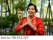 Portrait pretty Asian woman in a Chinese cheongsam smile and holding Golden amulet for Chinese New Year lucky symbol decorations, copy space. Стоковое фото, агентство Ingram Publishing / Фотобанк Лори
