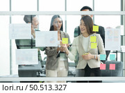 Young entrepreneurs in Asia Organize meetings to brainstorm and review information on glass board to get the best investment conclusion. Стоковое фото, агентство Ingram Publishing / Фотобанк Лори