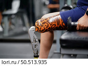 Young female with one prosthetic leg warms up by lifting light weights. Concept of living a woman’s life with a prosthetic limb. Стоковое фото, агентство Ingram Publishing / Фотобанк Лори