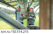 A team of electrical engineers is inspecting and maintaining solar panels at a solar panel site in the middle of a hundred acre field. Стоковое фото, агентство Ingram Publishing / Фотобанк Лори