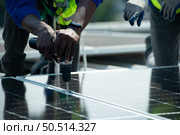 Both of Engineer in charge of solar panel installation The installation of solar energy conversion into electricity for a warehouse is currently being investigated. Стоковое фото, агентство Ingram Publishing / Фотобанк Лори