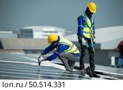 Both of Engineer in charge of solar panel installation The installation of solar energy conversion into electricity for a warehouse is currently being investigated. Стоковое фото, агентство Ingram Publishing / Фотобанк Лори