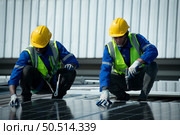 Both of Engineer in charge of solar panel installation The installation of solar energy conversion into electricity for a warehouse is currently being investigated. Стоковое фото, агентство Ingram Publishing / Фотобанк Лори