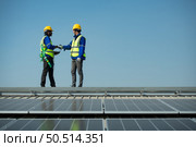 Both of Engineer in charge of solar panel installation The installation of solar energy conversion into electricity for a warehouse is currently being investigated. Стоковое фото, агентство Ingram Publishing / Фотобанк Лори