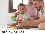 Parents with little girl have fun playing with your new toys in the bedroom together. Toys that enhance children’s thinking skills. Стоковое фото, агентство Ingram Publishing / Фотобанк Лори