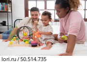 Parents with little girl have fun playing with your new toys in the bedroom together. Toys that enhance children’s thinking skills. Стоковое фото, агентство Ingram Publishing / Фотобанк Лори