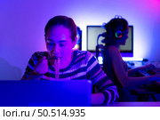 Asian women who rely heavily on computers to watch drama series until having to eat instant noodles in front of it, The game room has computers and LED neon lights that are spectacular. Стоковое фото, агентство Ingram Publishing / Фотобанк Лори