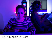 Asian women who rely heavily on computers to watch drama series until having to eat instant noodles in front of it, The game room has computers and LED neon lights that are spectacular. Стоковое фото, агентство Ingram Publishing / Фотобанк Лори