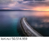Aerial view of lighthouse on the pier at colorful sunset in summer. Top drone view of lighthouse on jetty, blue sea and cloudy sky with sunlight. Landscape. Adriatic sea, Omis, Croatia. Travel	. Стоковое фото, агентство Ingram Publishing / Фотобанк Лори