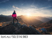 Young woman on mountain peak and beautiful mountain valley in haze at colorful sunset in autumn. Dolomites, Italy. Sporty girl, mountain ridges in fog, orange grass, trees, golden sun in fall. Hiking. Стоковое фото, агентство Ingram Publishing / Фотобанк Лори