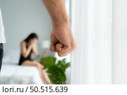The enraged man tightened his hand to hit the frightened woman in the background. The concept of family and physical abuse. Стоковое фото, агентство Ingram Publishing / Фотобанк Лори