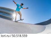 Skateboarder doing backside five-o grind trick in concrete skatepark. Стоковое фото, агентство Ingram Publishing / Фотобанк Лори