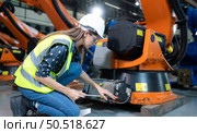 Female Technician Inspecting and repairing robotics arm in robots hangar and test the operation of the machine after being used for a while, as well as updating the software and calibration. Стоковое фото, агентство Ingram Publishing / Фотобанк Лори