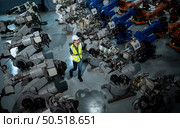 A female engineer installs a program on a robotics arm in a robot warehouse. And test the operation before sending the machine to the customer. Стоковое фото, агентство Ingram Publishing / Фотобанк Лори