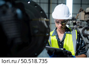 A female engineer installs a program on a robotics arm in a robot warehouse. And test the operation before sending the machine to the customer. Стоковое фото, агентство Ingram Publishing / Фотобанк Лори