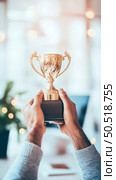 Golden Trophy Achievement: Hands Holding a Prize in a Bright Office Setting. Стоковое AI-изображение, AI-художник Данила Большаков / Фотобанк Лори