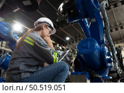 A female engineer installs a program on a robotics arm in a robot warehouse. And test the operation before sending the machine to the customer. Стоковое фото, агентство Ingram Publishing / Фотобанк Лори