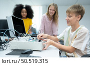 Youngsters utilizing the hand robot technology are having fun learning the electronic circuit board and hand robot controller of robot technology, which is one of the STEM courses. Стоковое фото, агентство Ingram Publishing / Фотобанк Лори