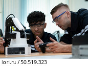 The robotic hand technology teacher is instructing new pupils on how to construct robotic hands for a variety of industrial applications. Стоковое фото, агентство Ingram Publishing / Фотобанк Лори
