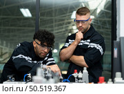 The robotic hand technology teacher is instructing new students on how to use electronic circuit boards and robotic hand commands for a variety of industrial applications. Стоковое фото, агентство Ingram Publishing / Фотобанк Лори