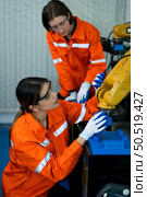 In an electronic parts facility, two female engineers In the plant, inspecting and testing robotic hands used in the production of electronic components. Стоковое фото, агентство Ingram Publishing / Фотобанк Лори