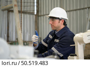 Young male engineers with experience are maintaining and testing the functionality of welding robots. After the hardwork of welding robots. Стоковое фото, агентство Ingram Publishing / Фотобанк Лори