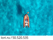 Aerial view of beautiful orange boat in blue sea at sunset in summer. Sardinia, Italy. Top drone view of motorboat, ocean with transparent azure water. Travel. Tropical landscape. Yachting. Seascape. Стоковое фото, агентство Ingram Publishing / Фотобанк Лори