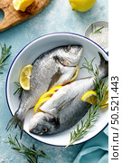 Fresh raw dorado fish cooking with lemon and rosemary. Sea bream, dorado. Seafood, healthy food. Top view. Стоковое фото, агентство Ingram Publishing / Фотобанк Лори