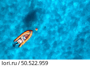 Aerial view of beautiful orange boat in blue sea at sunset in summer. Sardinia, Italy. Top drone view of motorboat, ocean with transparent azure water. Travel. Tropical scenery. Yachting. Seascape. Стоковое фото, агентство Ingram Publishing / Фотобанк Лори