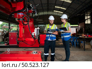 Both of engineers installing and testing a large robotic arm. before sending it to customers for use in the industry. Стоковое фото, агентство Ingram Publishing / Фотобанк Лори