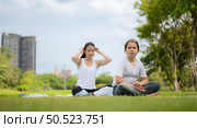 Young female and little girl with outdoor activities in the city park, Yoga is her chosen activity. Стоковое фото, агентство Ingram Publishing / Фотобанк Лори