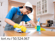 Young woman cleaning the table in the kitchen. Housekeeping and housekeeping concept. Стоковое фото, агентство Ingram Publishing / Фотобанк Лори