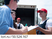 Delivery man handing over parcel boxes to customer in front of truck and the customer signs for the box in the document. Стоковое фото, агентство Ingram Publishing / Фотобанк Лори