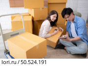 Young asian couple checking boxes being transported into new home with tablet. Стоковое фото, агентство Ingram Publishing / Фотобанк Лори