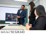 Diverse team of businessmen and engineers consultation on the engineering of a wind turbine that converts wind energy to electricity in the office. Стоковое фото, агентство Ingram Publishing / Фотобанк Лори
