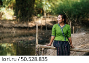 Portrait Asian young pretty woman wearing  beautiful cloths stand and smiling while relaxing in countryside thailand, copy space. Стоковое фото, агентство Ingram Publishing / Фотобанк Лори