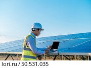 Young Asian technician man checking operation of sun and cleanliness of photovoltaic solar panel and typing on laptop computer while working in solar farm. Стоковое фото, агентство Ingram Publishing / Фотобанк Лори