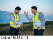 Young chief engineer is complain the trainee man on site of solar power plant, solar panel on background. Стоковое фото, агентство Ingram Publishing / Фотобанк Лори