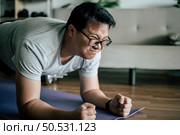 Funny overweight man in glasses try to planking on the floor doing workout, copy space. Стоковое фото, агентство Ingram Publishing / Фотобанк Лори