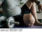 Funny overweight man sitting exhausted down on the floor after workout with dumbbell, copy space. Стоковое фото, агентство Ingram Publishing / Фотобанк Лори