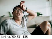 Funny overweight man in glasses closed his eyes and lying exhausted down on the floor after workout, copy space. Стоковое фото, агентство Ingram Publishing / Фотобанк Лори