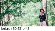 Young pretty woman use digital camera taking a photo beautiful nature while camping in forest with happiness, copy space. Стоковое фото, агентство Ingram Publishing / Фотобанк Лори