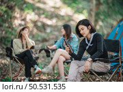 Selective focuse, beautiful Asian woman and friends travelers  relaxing at front of camping tent, They enjoy to talking and drinking beer with fun and happy together. Стоковое фото, агентство Ingram Publishing / Фотобанк Лори