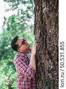 Portrait of Happy Asian man hugging a tree in forest. Protecting and love nature. Environment and ecology concept. Стоковое фото, агентство Ingram Publishing / Фотобанк Лори